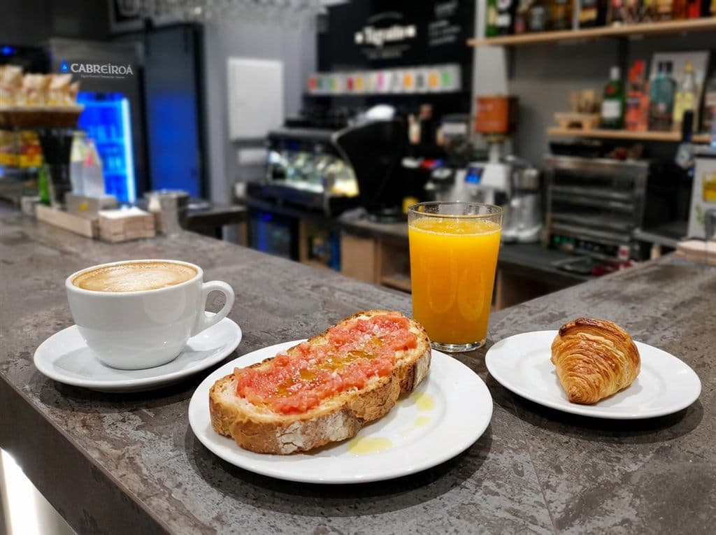Desayuno con café, tostada y zumo natural en la barra de Cafetería mac, Ferrol